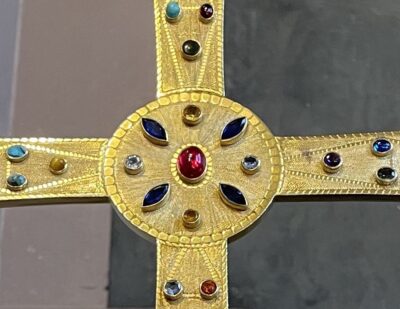 The cross is adorned with 94 semiprecious and synthetic stones, both cabochon and faceted. The diverse stones appear almost random on one side, but the pattern is duplicated exactly on the other side.